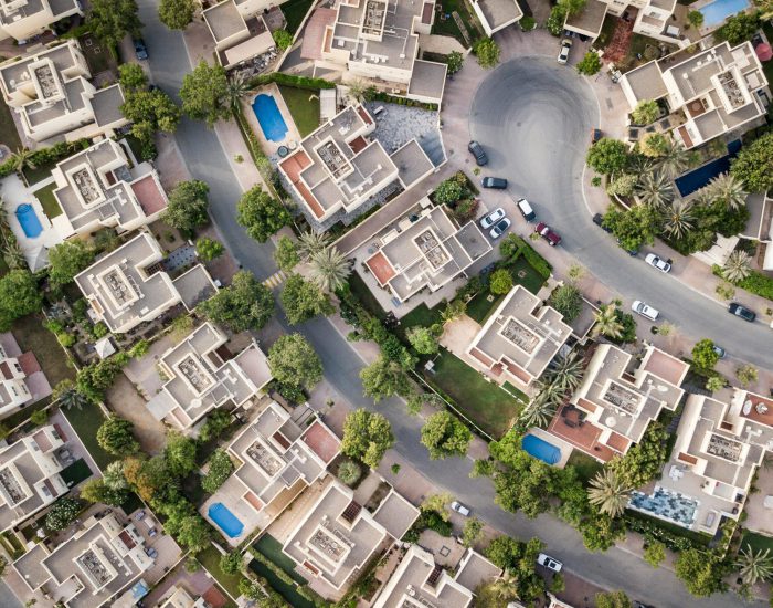Explore a stunning aerial view of a residential area in Dubai with lush greenery and swimming pools.